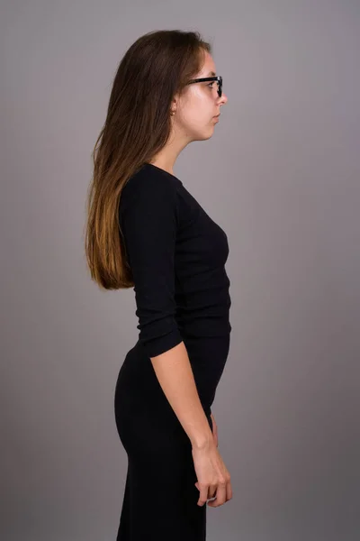 Portrait of young beautiful woman against gray background — Stock Photo, Image