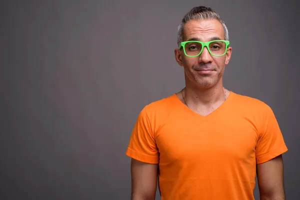 Handsome Persian man with gray hair wearing orange t-shirt — Stock Photo, Image