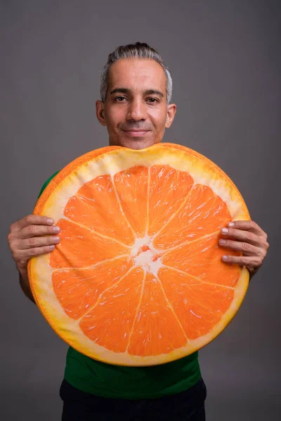 Bello uomo persiano con i capelli grigi in possesso di una grande fetta di arancione — Foto Stock