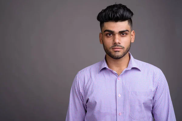 Junger gutaussehender indischer Geschäftsmann vor grauem Hintergrund — Stockfoto