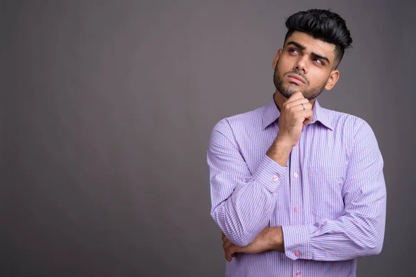 Junger gutaussehender indischer Geschäftsmann vor grauem Hintergrund — Stockfoto