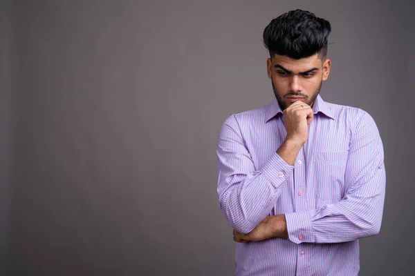 Junger gutaussehender indischer Geschäftsmann vor grauem Hintergrund — Stockfoto