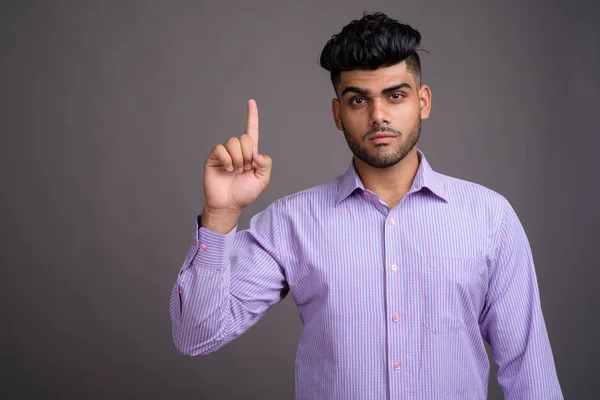 Mladý hezký indický podnikatel proti šedé pozadí — Stock fotografie