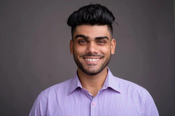 Young handsome Indian businessman against gray background — Stock Photo, Image