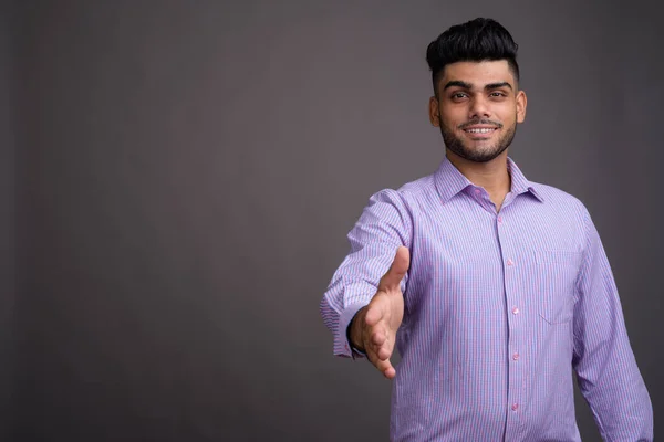 Young handsome Indian businessman against gray background — Stock Photo, Image