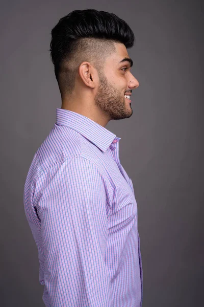 Young handsome Indian businessman against gray background — Stock Photo, Image