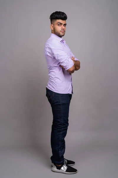 Young handsome Indian businessman against gray background — Stock Photo, Image