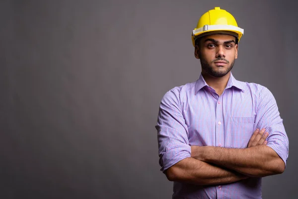 Jovem bonito indiana empresário vestindo hardhat contra cinza b — Fotografia de Stock