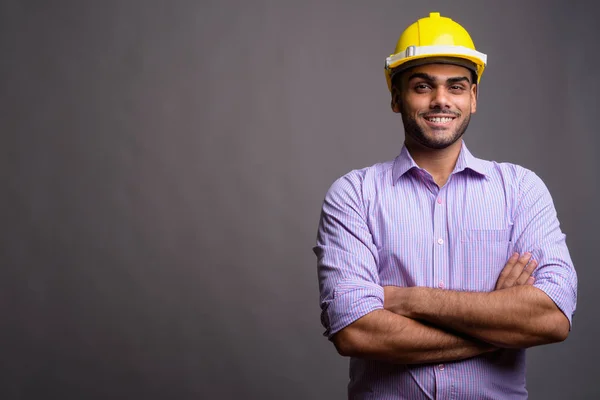 Jovem bonito indiana empresário vestindo hardhat contra cinza b — Fotografia de Stock