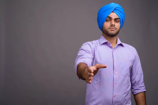 Junge hübsche indische Geschäftsmann trägt Turban gegen grauen ba — Stockfoto