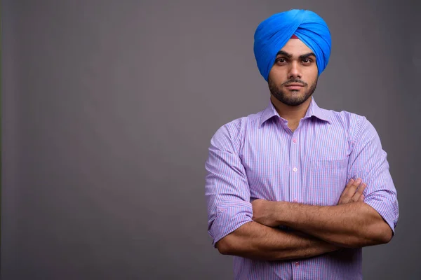 Молодий красивий індійський бізнесмен носити тюрбан проти сірих ба — стокове фото