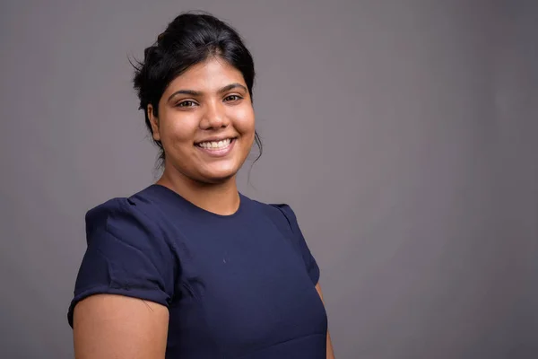 Genç kilolu güzel Hintli kadın gri bir arka plana dayanır