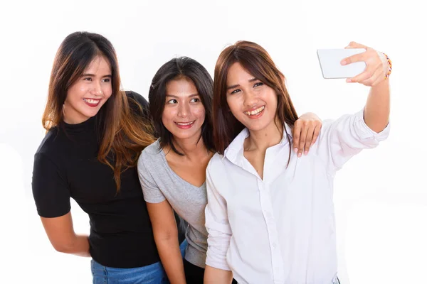 Студийный снимок трех счастливых молодых азиатских подруг, улыбающихся — стоковое фото