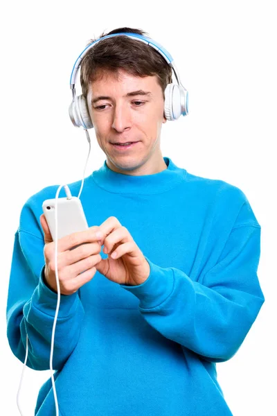 휴대 전화를 사용 하는 동안 음악을 듣고 남자의 스튜디오 샷 — 스톡 사진