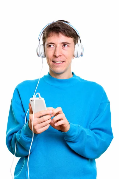 Pensativo hombre feliz sonriendo mientras escucha música y usando —  Fotos de Stock