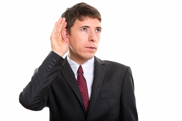 Studio shot of thoughtful businessman listening against white background — Stock Photo, Image