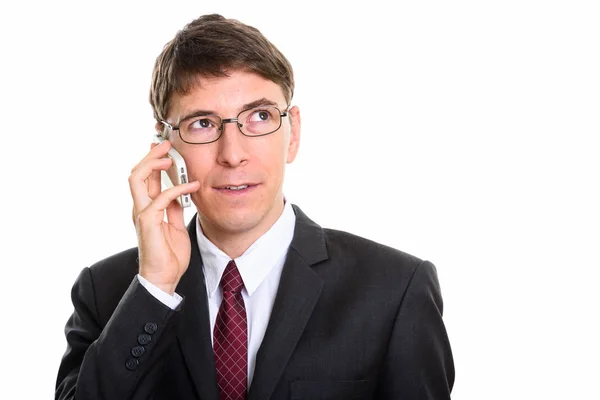 Studio shot of businessman talking on mobile phone while thinkin — Stock Photo, Image