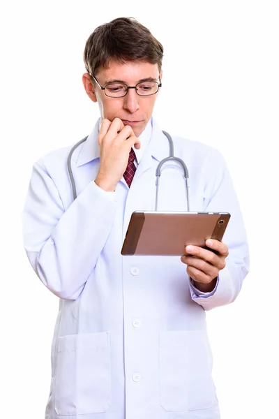 Студийный снимок человека-врача, держащего цифровой планшет в раздумьях — стоковое фото
