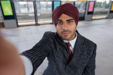 Hintli işadamı selfie cep telefonu ile çekerken tren istasyonunda oturan