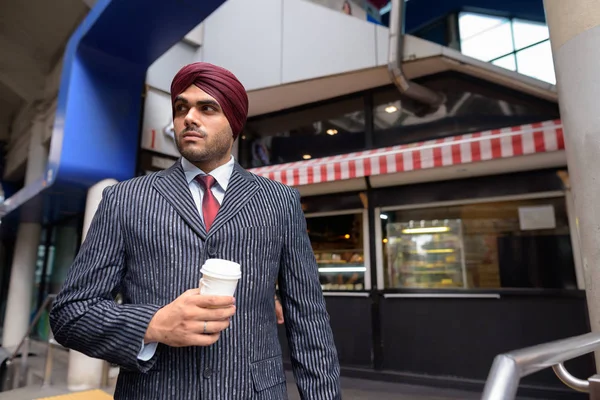 Jeune bel homme d'affaires indien sikh tenant tasse de café jetable — Photo
