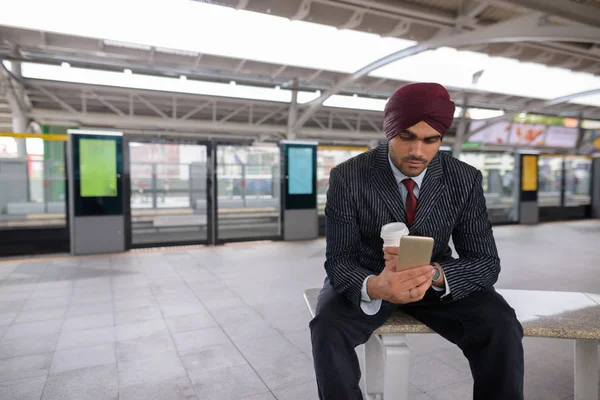 Portrait of young handsome Indian Sikh businessman wearing turban while exploring the city of Bangkok, Thailand