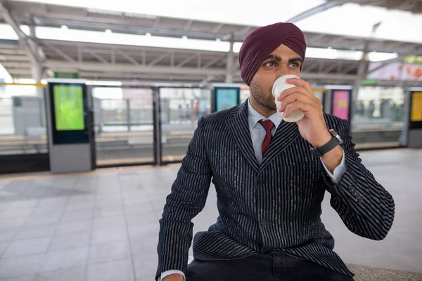 Indian businessman drinking coffee at train station