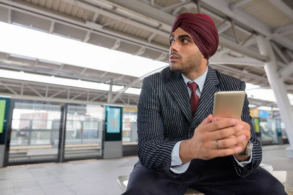 Indian businessman using mobile phone at train station — Stock Photo, Image
