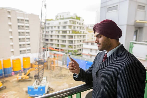 Indian businessman looking at construction development site with skyscrapers