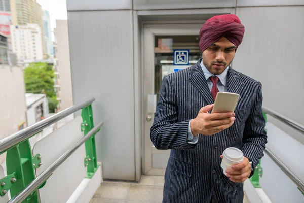 Indian businessman with turban outdoors in city using phone