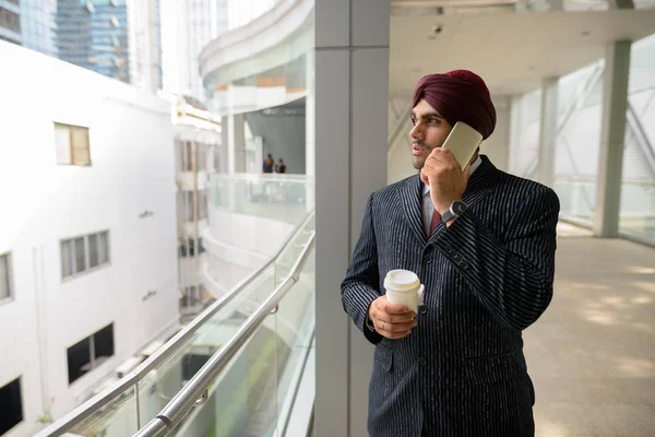 Homme d'affaires indien en ville parlant au téléphone et tenant une tasse de café — Photo