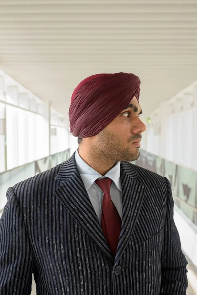 Portrait of Indian businessman with turban thinking outdoors in city