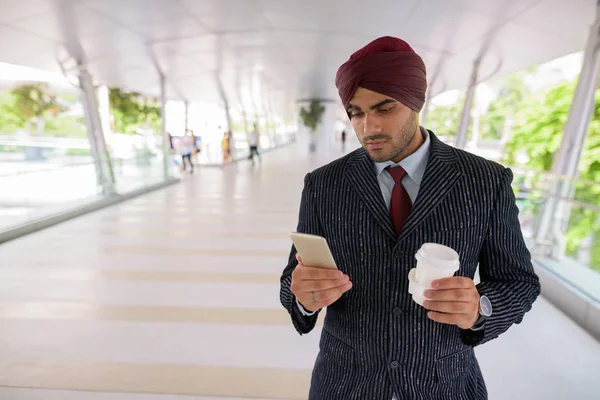 Homme d'affaires indien en ville utilisant le téléphone et tenant tasse de café — Photo