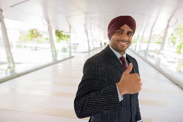 Boldog indiai üzletember ad a hüvelykujjával felfelé a szabadban városban — Stock Fotó