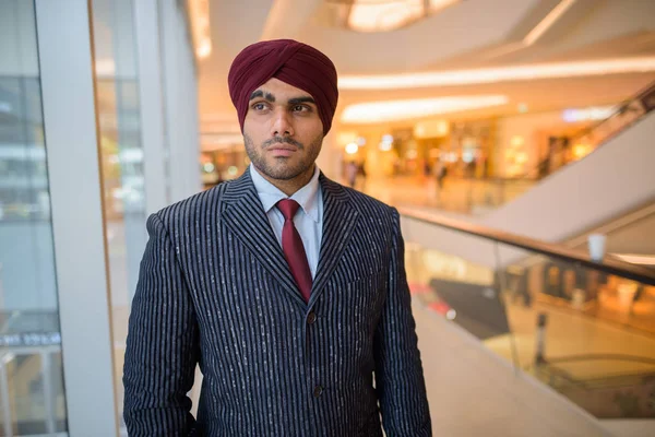 Portrait of Indian businessman with turban looking through window