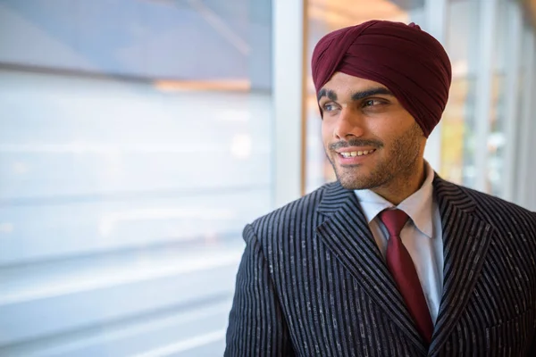 Heureux homme d'affaires indien avec turban regardant par la fenêtre — Photo