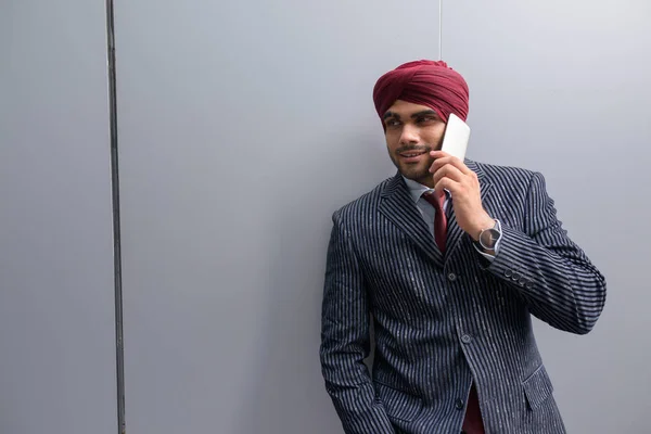 Indian businessman with turban outdoors in city talking on phone