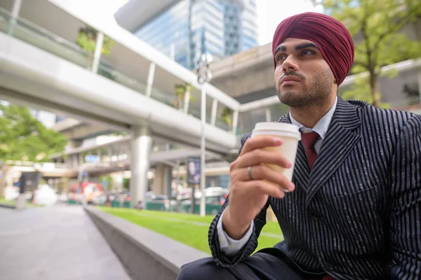 Homme d'affaires indien assis à l'extérieur en ville tout en prenant une pause café — Photo