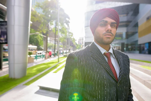 Portrait of Indian businessman outdoors in city with lens flare
