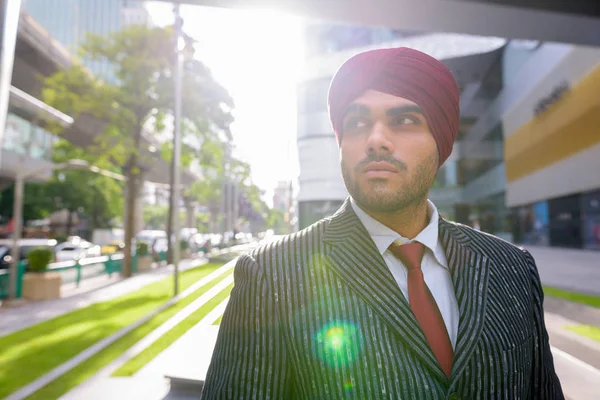 Portrait of Indian businessman outdoors in city with lens flare
