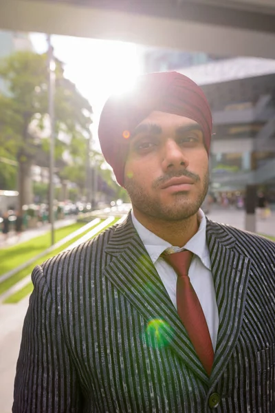 Portrait of Indian businessman outdoors in city with lens flare