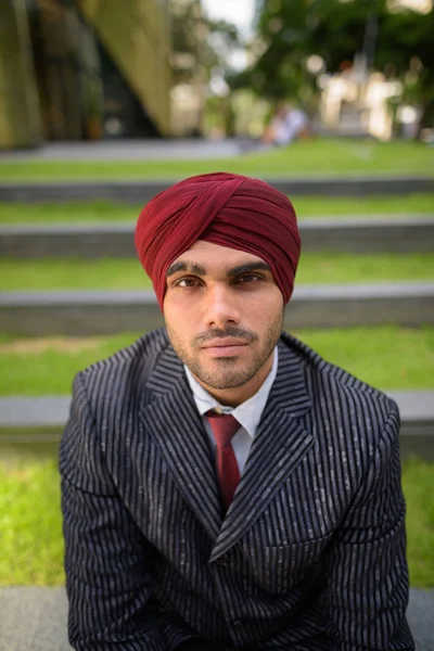 Uomo d'affari indiano con turbante seduto all'aperto in città — Foto Stock