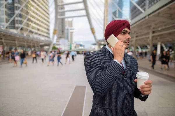 Indian businessman outdoors in city talking on phone — Stock Photo, Image