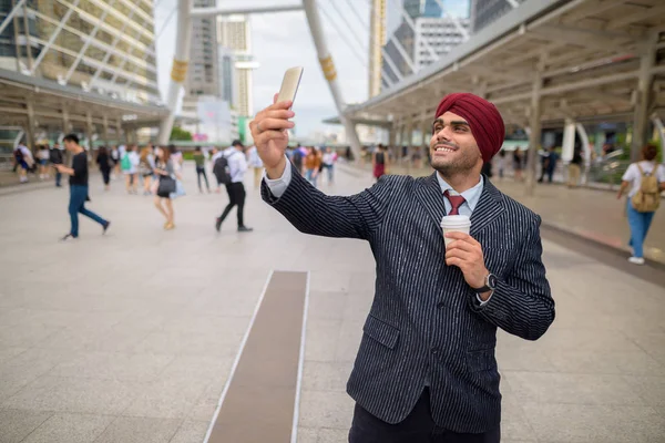 Indian businessman outdoors in city using mobile phone to take selfie — Stock Photo, Image
