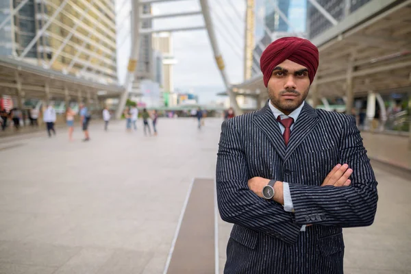 Indian businessman with turban outdoors in city with arms crossed