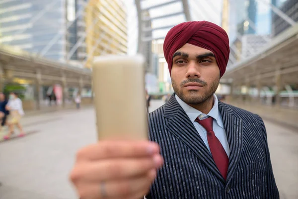 Indian businessman with turban outdoors in city using mobile phone