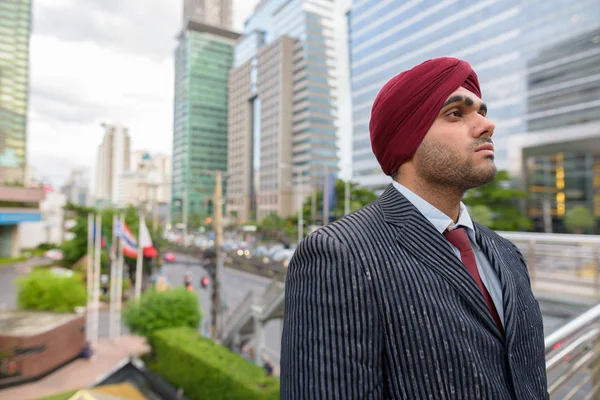 Portrait of Indian businessman with turban thinking in city