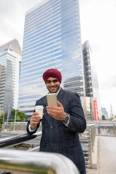Indian businessman with turban outdoors in city using mobile phone — Stock Photo, Image