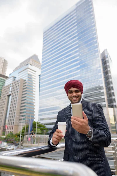 Indian businessman with turban outdoors in city using mobile phone — Stock Photo, Image