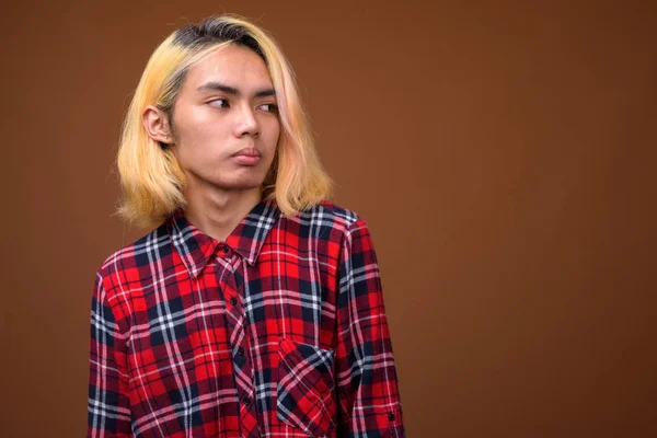 Młoda Azji mężczyzna nosić stylowe ubrania na brązowym tle — Zdjęcie stockowe