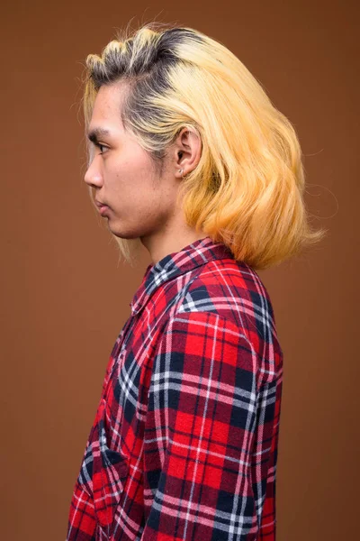 Giovane uomo asiatico indossa abiti alla moda contro sfondo marrone — Foto Stock